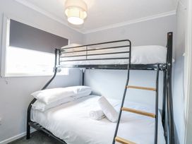 A bedroom with a bunk bed, window with blind, and folded towels on the lower bed at California Summers in California, Norfolk