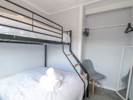 A bedroom with a black metal bunk bed a gray chair an open closet with hangers and a full-length mirror at California Summers in California Norfolk