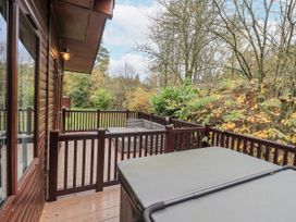 A deck with a hot tub and outdoor furniture at Damson Lodge Thirlmere 8, White Cross Bay, Windermere