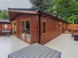 A log cabin with a deck and wooden railing at Ridgway Lodge Calgarth 40, White Cross Bay near Windermere