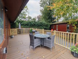 A deck with a table and chairs at Buttermere Lodge, Glade 5, Fallbarrow Park near Bowness on Windermere
