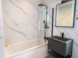 A bathroom with a bathtub, shower, and sink at Rydal Lodge in Grasmere 24, White Cross Bay near Windermere