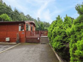 An outdoor view of a lodge with a wooden deck at Birthwaite Lodge, Fellside 6, Limefitt Park near Windermere