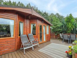 An outdoor area with a wooden lodge and seating at Birthwaite Lodge Fellside 6 Limefitt Park near Windermere