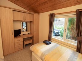 A bedroom with a bed and a wardrobe at Birthwaite Lodge near Limefitt Park