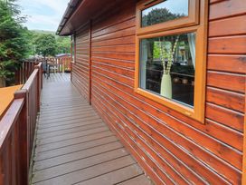 An outdoor view of a wooden deck with a window and a vase at Birthwaite Lodge, Fellside 6, Limefitt Park near Windermere