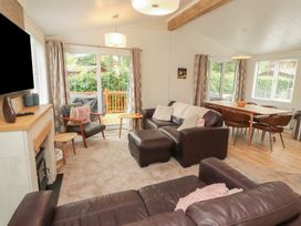 A living room with a sofa and dining area at Beech Grove Lodge, Glade 17, Fallbarrow Park near Bowness on Windermere