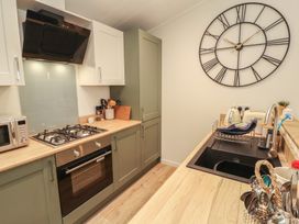 A kitchen with cabinets, cooker, sink, and clock at Beech Grove Lodge, Glade 17, Fallbarrow Park near Bowness on Windermere