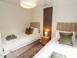 A bedroom with two beds and a bedside table at Beech Grove Lodge, Glade 17, Fallbarrow Park near Bowness on Windermere