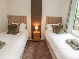 A bedroom with two single beds and a bedside table at Beech Grove Lodge, Glade 17, Fallbarrow Park near Bowness on Windermere