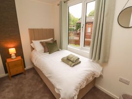 A bedroom with a bed and window at Beech Grove Lodge, Glade 17, Fallbarrow Park near Bowness on Windermere