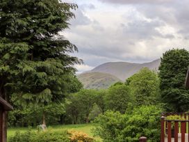 A garden with trees and bushes with mountains and cloudy sky in the background at Pheasant's Nest Kirkstone 11 Limefitt Park near Windermere
