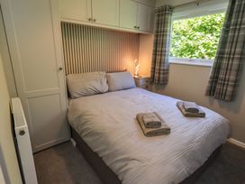 A bedroom with a bed and bedside table at Badgers Hollow Lodge, Grasmere 30, White Cross Bay near Windermere