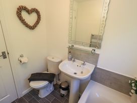 A bathroom with a sink, toilet, bathtub, and mirror at Badgers Hollow Lodge Grasmere 30, White Cross Bay near Windermere