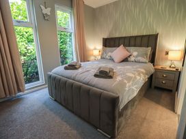 A bedroom with a bed and windows at Badgers Hollow Lodge, Grasmere 30, White Cross Bay near Windermere