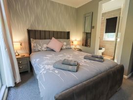 A bedroom with a bed and nightstand at Badgers Hollow Lodge, Grasmere 30, White Cross Bay near Windermere