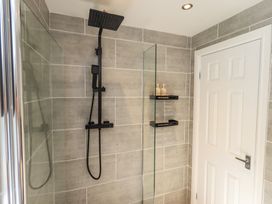 A shower with modern fixtures and a door at Badgers Hollow Lodge Grasmere 30, White Cross Bay near Windermere
