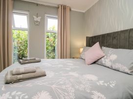 A bedroom with a bed and windows at Badgers Hollow Lodge, Grasmere 30, White Cross Bay near Windermere