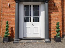 An entryway with a white door and decorative plants at Bodaioch Hall Trefeglwys near Caersws