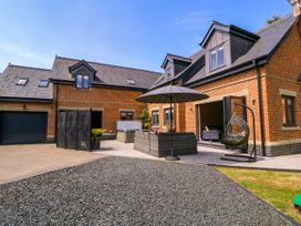 An outdoor patio area with seating and an umbrella at Thornbury, Barnard's Green, Malvern