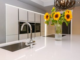 A kitchen with a sink and sunflowers in a vase at Thornbury in Barnard's Green, Malvern