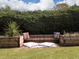 A garden with a wooden bench and cushions at Thornbury, Barnard's Green, Malvern