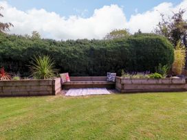A garden with planters, grass, and cushions at Thornbury, Barnard's Green, Malvern