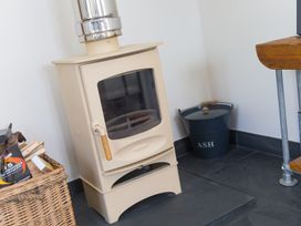 A wood stove with a chimney and ash bucket in a living room at Scilly Stack in Penzance