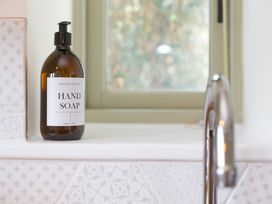 A hand soap bottle and faucet next to a window in a bathroom at Scilly Stack in Penzance