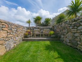 A garden with a stone wall and wooden benches at Scilly Stack in Penzance