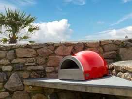 A wood-fired oven on a table next to a stone wall at Scilly Stack in Penzance
