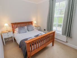 A bedroom with a bed and nightstands at Crown Cottage in Penally