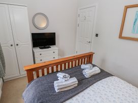 A bedroom with a bed and a television at Crown Cottage in Penally