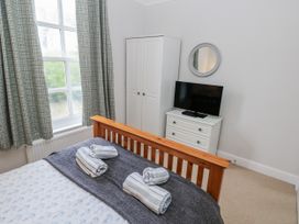 A bedroom with a bed and a television at Crown Cottage in Penally
