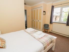 A bedroom with a bed, wardrobe, and window at Tynewydd Fields in Cross Inn