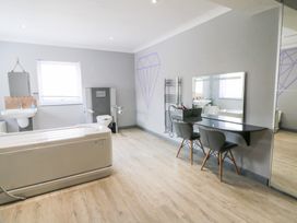 A bathroom with a bathtub, sink, toilet, and mirror at Tynewydd Fields in Cross Inn