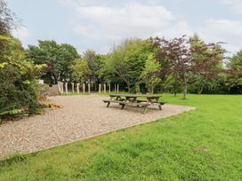 A garden with a picnic table and trees at Tynewydd Fields in Cross Inn