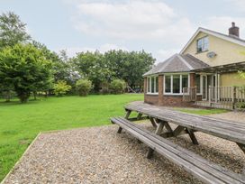 A garden with a house, deck and grassy area at Tynewydd Fields in Cross Inn