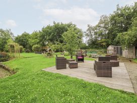 A garden with a wooden deck and chairs at Tynewydd Fields in Cross Inn