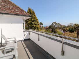 A balcony with white chairs and a view of trees and rooftops at Harbour Lights in Torquay