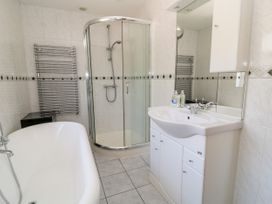 A bathroom with a bathtub shower enclosure sink with mirror and towel radiator at Harbour Lights in Torquay