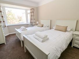 A bedroom with two single beds with folded towels on white bedding and a large window with patterned curtains at Harbour Lights in Torquay