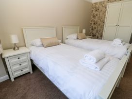 A bedroom with two single beds bedside tables lamps wardrobe and folded towels at Harbour Lights in Torquay