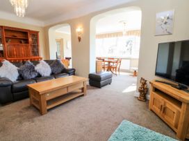 A living room with a sofa and coffee table next to a TV on a wooden stand at Harbour Lights in Torquay