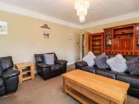 A living room with leather armchairs wooden coffee table and a wooden cabinet at Harbour Lights in Torquay
