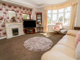 A living room with a fireplace television a beige sofa armchair and a round rug at Harbour Lights in Torquay