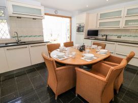 A kitchen with a wooden dining table set with dishes and surrounded by wicker chairs at Harbour Lights in Torquay