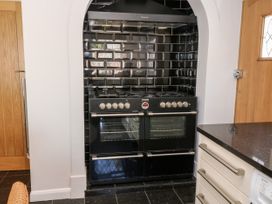 A black stove with multiple burners and ovens set into a tiled alcove with black glossy subway tiles in a kitchen at Harbour Lights in Torquay