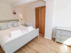 A bedroom with a bed with folded towels pillows wooden doors a bedside table and a chest of drawers at Harbour Lights in Torquay