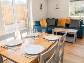 A dining table set for four with plates and glasses next to a blue sofa with cushions and a coffee table in a living room at Harbour Lights in Torquay